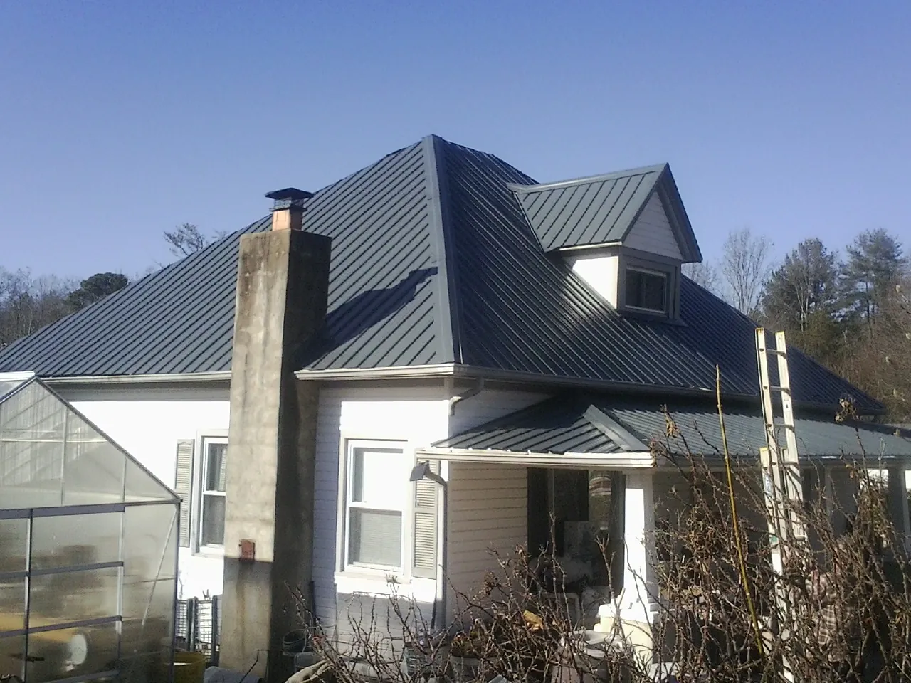 Dark blue standing seam metal roof on a white farmhouse with dormer — Slate & Tile Roof Repair by Roofing Brothers in Mechanicsville