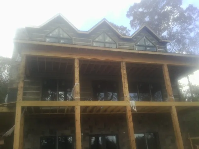 Dormers and porch framing on a large log home under construction — Roof Coating work by our crew in Mechanicsville
