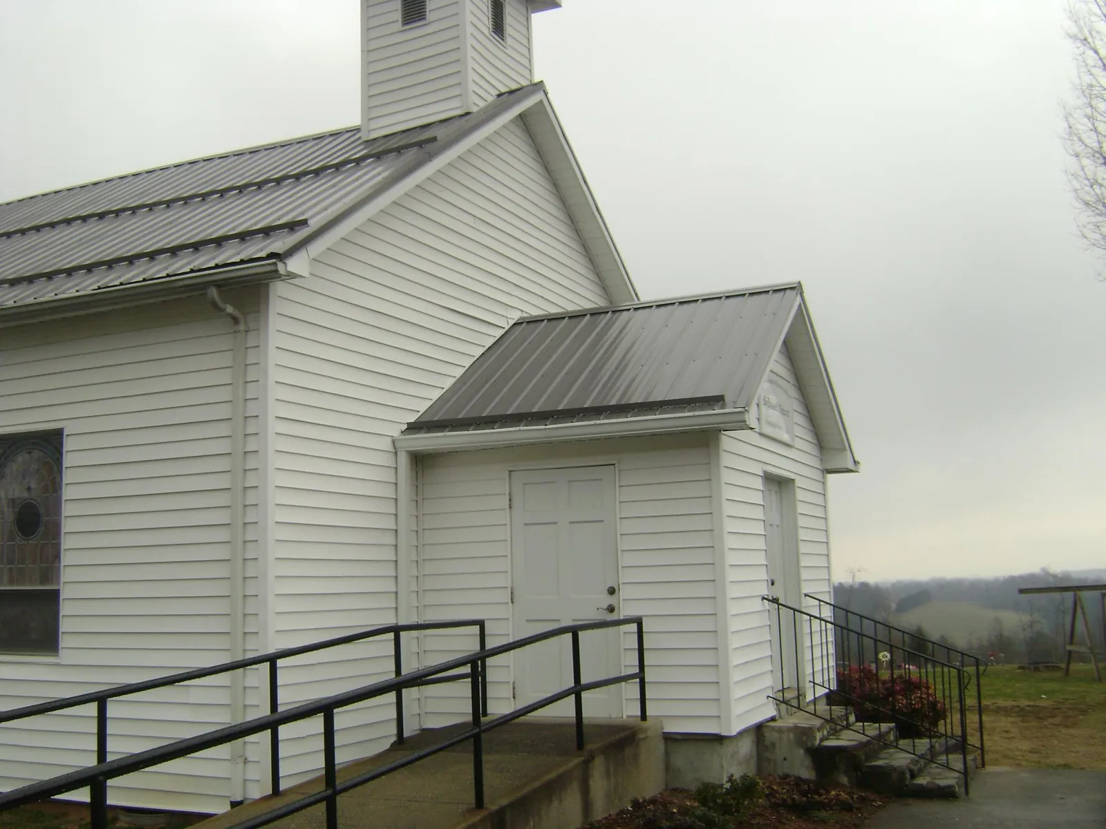 Gray metal roof on a white clapboard church with a steeple in Mechanicsville